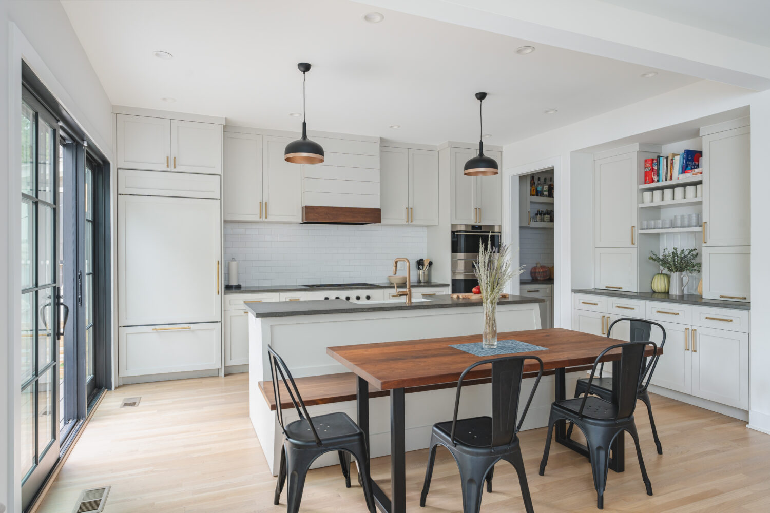Transitional Washington DC kitchen renovation featuring custom white shaker cabinetry, natural white oak bench and accents, built in island seating, and pendant lighting by Hammer Design Build Remodel