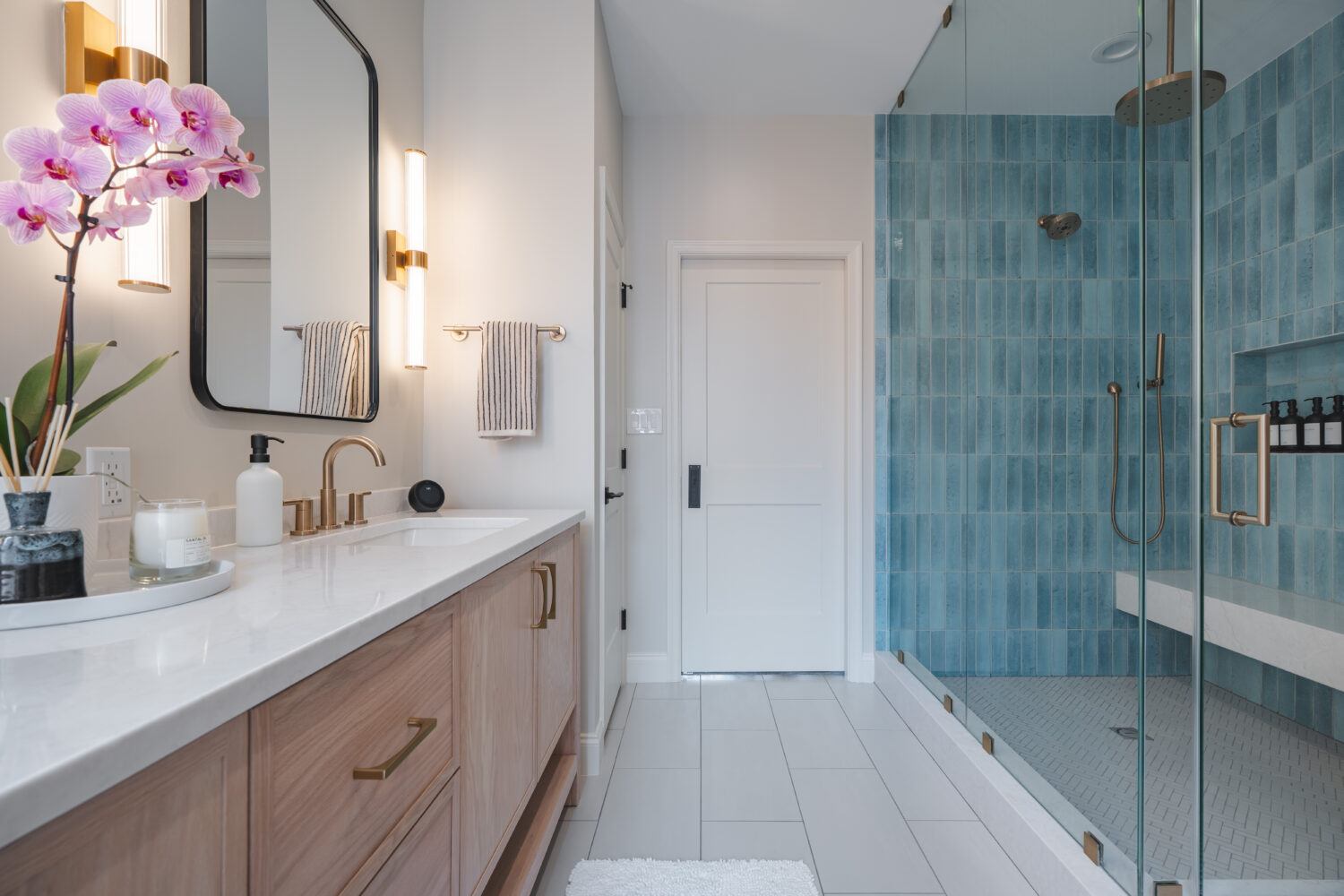 Luxury primary bathroom renovation in DC home with custom light wood double vanity, white countertops, brass fixtures, and designer sconce lighting by Hammer Design Build Remodel